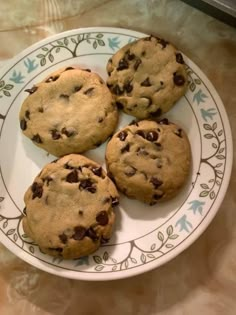 four chocolate chip cookies on a white and green plate