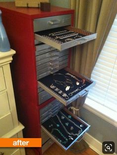 a red cabinet with jewelry on it next to a window