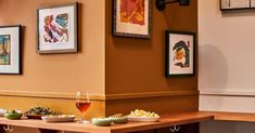 a table topped with bowls of food next to framed pictures on the wall above it