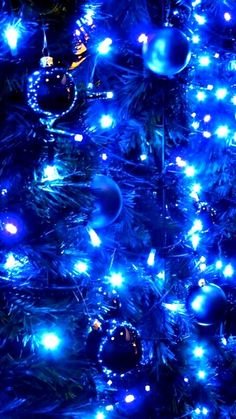 a blue christmas tree with ornaments and lights