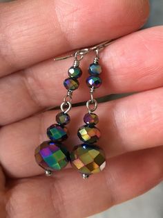 a pair of multicolored glass beaded earrings on a person's hand