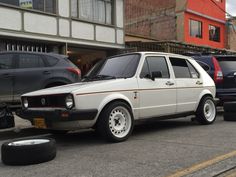 a white car parked in front of a building next to other cars on the street