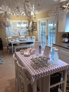 a dining room table covered in purple and white checkered cloth with place settings on it