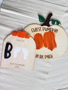 two wooden pumpkin shaped magnets with baby's feet and name on each one