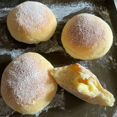 three rolls with powdered sugar on them sitting on a baking sheet