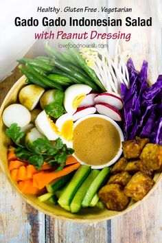 gado gado indonesian salad with peanut dressing in a bowl on a wooden table