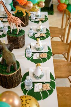 a table set up for a party with balloons and giraffe figurines