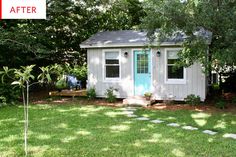 a small white shed sitting in the middle of a lush green yard next to trees