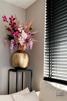 a vase filled with flowers sitting on top of a table next to a white pillow