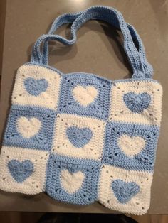 a crocheted blue and white purse with hearts