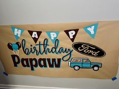 a happy birthday banner hanging on the wall with balloons and an suv in front of it