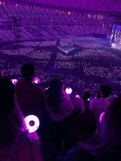 people sitting in the middle of a large room with purple lights on their heads and hands