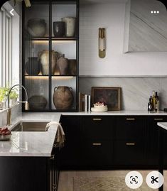 a kitchen with marble counter tops and black cabinets, along with an open shelving unit