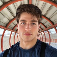 a man taking a selfie in front of a metal structure with orange railings