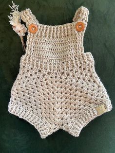 a crocheted baby romper with buttons on it