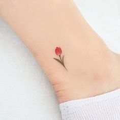 a small red flower tattoo on the ankle