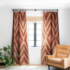 an orange chair sitting in front of a window next to a potted green plant