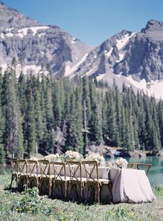 a long table set up in the middle of a field with mountains in the background