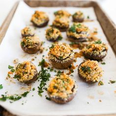 small stuffed mushrooms on a baking sheet with parsley sprinkled on top, ready to be eaten