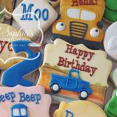 decorated cookies with cars and trucks are on a wooden table, along with the words happy birthday