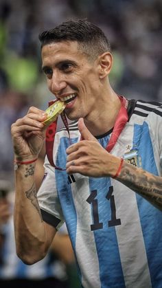 a man eating food while standing on top of a soccer field with his hands in his mouth