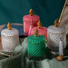 four glass jars with gold trimmings are sitting on a table