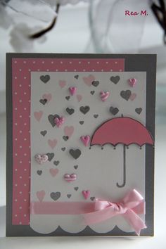 a card with an umbrella on it and hearts all over the place, as well as pink bows