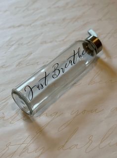 a glass bottle with the word just breathe written on it sitting on a bed sheet