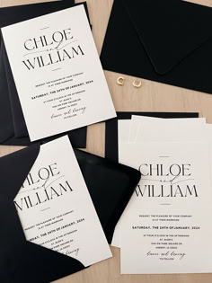 black and white wedding stationery is laid out on a table with envelopes, rings, and other items