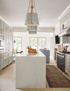 a large kitchen with an island in the middle and a chandelier hanging from the ceiling