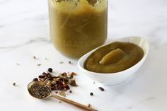 there is a spoon with some food in it next to a jar filled with liquid