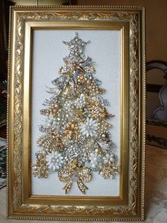 a christmas tree made out of pearls in a gold frame on top of a table