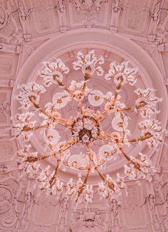 a chandelier hanging from the ceiling in a room with pink walls and ceilings