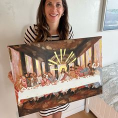 a woman holding up a painting with the last supper on it