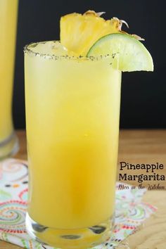 two glasses filled with pineapple margarita on top of a table