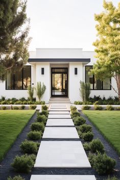 a white house with grass and trees in the front yard, leading to it's entrance