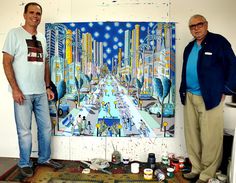 two men standing in front of a painting on the wall with paintbrushes all over it