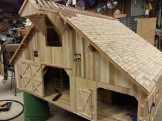 a large wooden building with two windows and doors on the roof, in a garage