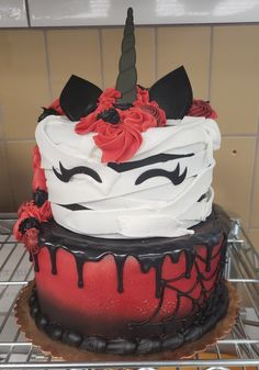 a cake decorated with red and black icing on top of a metal rack in a kitchen