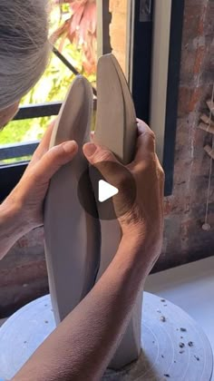 a woman is making a vase out of clay with her hands on the top of it