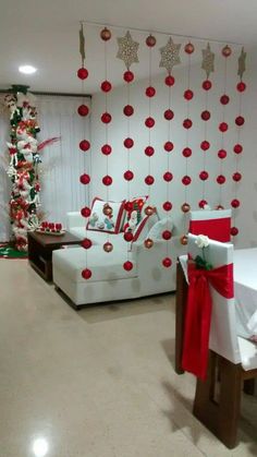 a living room decorated for christmas with red and white decorations on the wall, couches and table