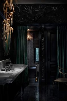 a dark bathroom with green curtains and chandelier hanging from the ceiling, along with marble counter tops