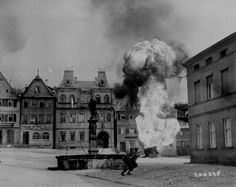 black and white photograph of an explosion in front of buildings