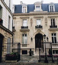 an old building with wrought iron gates and flowers on the front door is pictured in this image