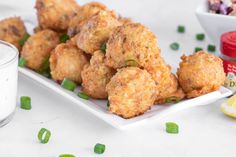 some fried food on a white plate with green onions and seasoning sprinkles