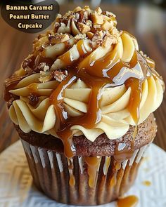 a chocolate cupcake with caramel icing and nuts on top, sitting on a white plate