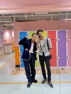 two men taking a selfie in front of lockers