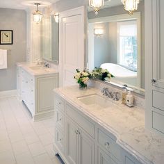 a white bathroom with marble counter tops and double sinks