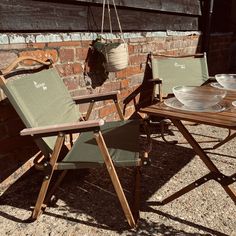 two lawn chairs sitting next to each other in front of a brick wall