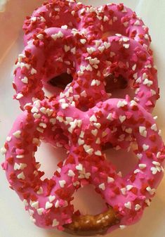 a pink donut with white sprinkles on it sitting on a plate